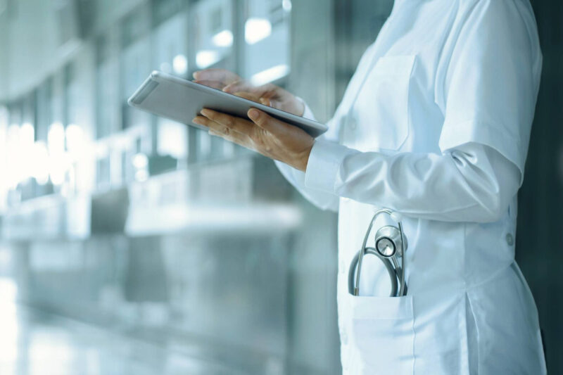 Mensch in Kittel mit Unterlagen in der Hand. (Foto: ipopba)