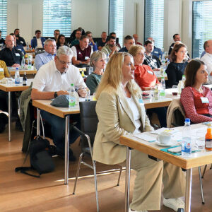 Teilnehmende einer Konferenz in Stuhlreihen angeordnet.