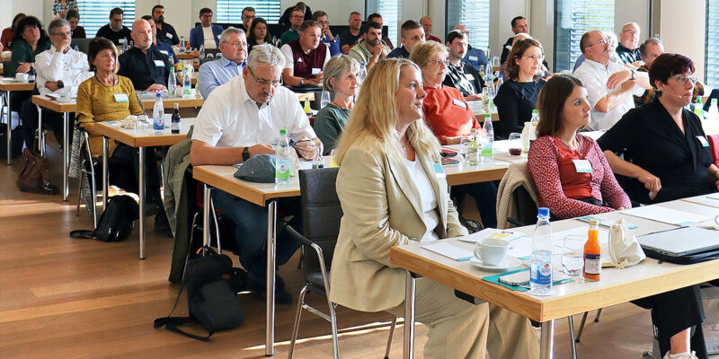 Teilnehmende einer Konferenz in Stuhlreihen angeordnet.