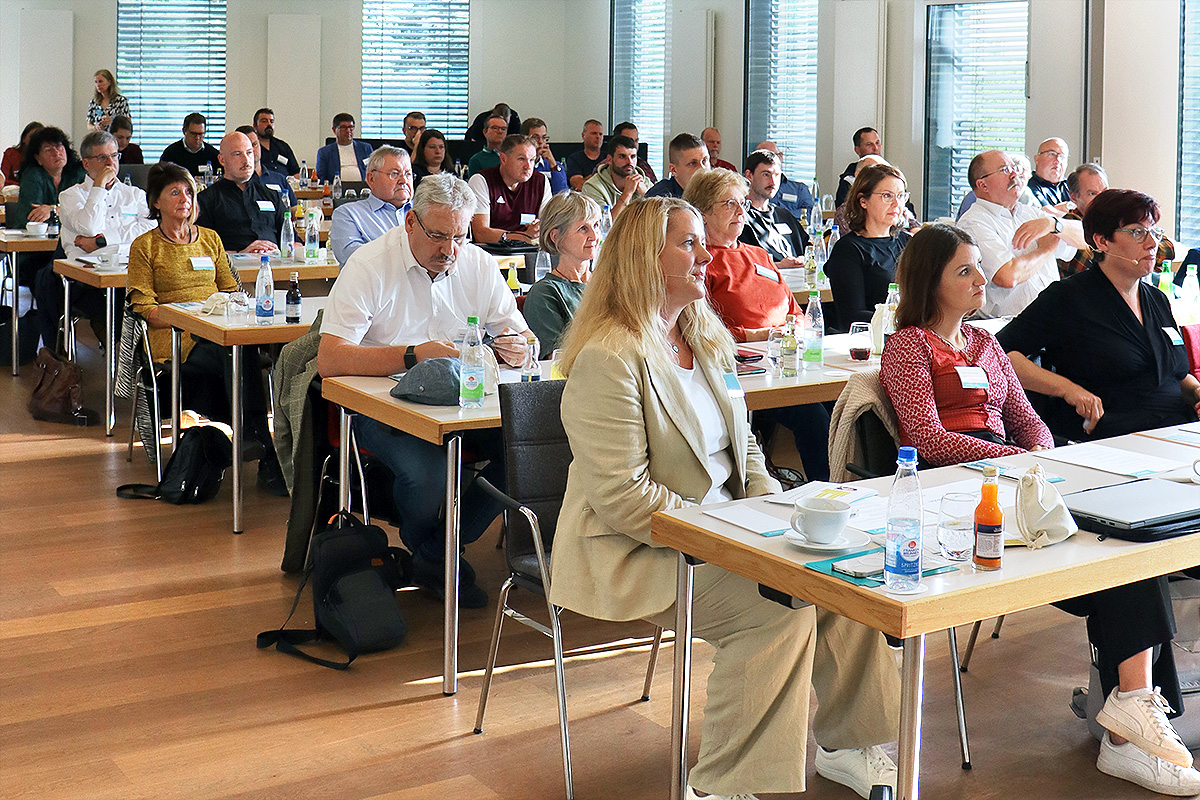 Teilnehmende einer Konferenz in Stuhlreihen angeordnet.