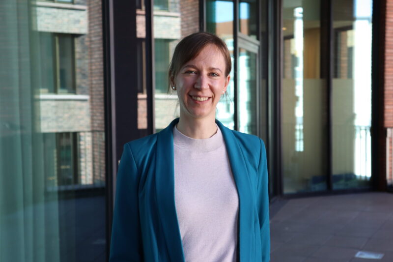 Agnes Höferle – Foto vor Fenster, Frau in Blazer (petrol)