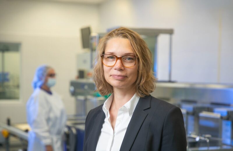 Frau in Businessoutfit, im Hintergrund Labor (Bild: Christian Kielmann)